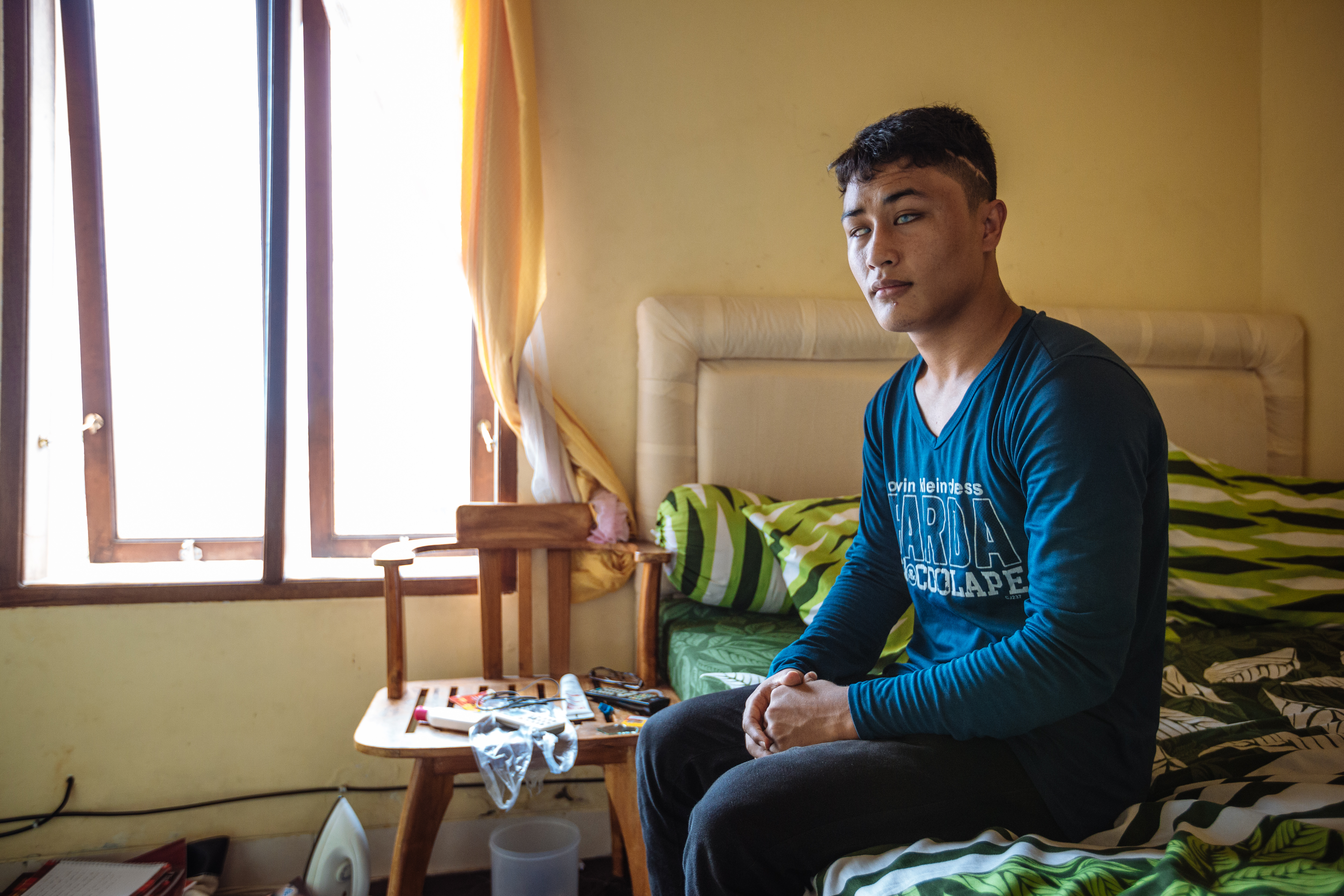 (c) NRC A young blind boy sits on a bed